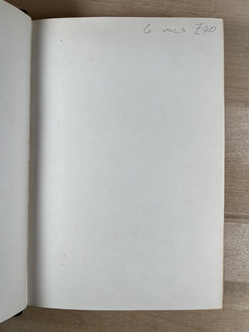 May include: Open notebook with blank white pages. Handwritten text in the upper right corner reads "6 vols 140". The notebook is open on a light-colored wooden surface.