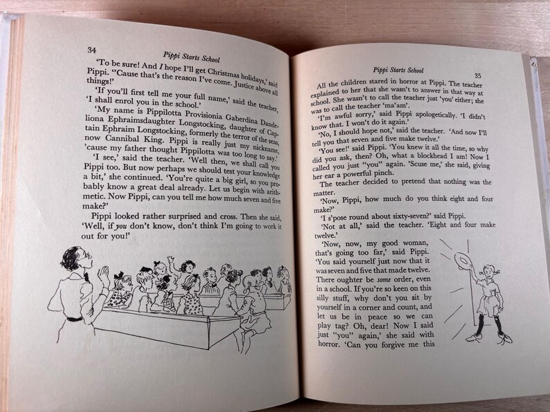 May include: An open book showing pages 34 and 35 of the story Pippi Starts School. The text is printed in black ink on off-white paper. Black and white line art illustrations depict a classroom scene with a teacher and students.