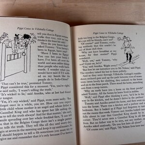 Puede incluir: Un libro abierto con ilustraciones y texto. Las p&aacute;ginas muestran dibujos en blanco y negro de personajes y texto de la historia "Pippi Comes to Villekulla Cottage". El libro est&aacute; abierto sobre una superficie de madera.