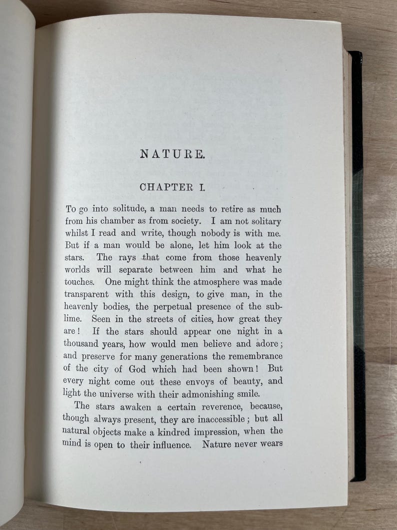 May include: Open book with text titled "NATURE" and "CHAPTER I". The text describes the need for solitude and the beauty of the stars. The pages are aged with a slightly yellowed tone, and the text is in black.