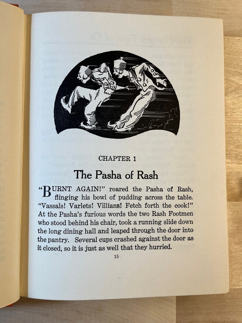 K&ouml;nnte beinhalten: Eine Schwarzwei&szlig;illustration von zwei Figuren, die vor einer Sch&uuml;ssel Pudding davonlaufen. Der Text "Burnt Again!" steht &uuml;ber der Illustration. Der Text "The Pasha of Rash" steht in gr&ouml;&szlig;erer Schrift unter der Illustration. Der Text "Chapter 1" steht in kleinerer Schrift unter dem Titel.