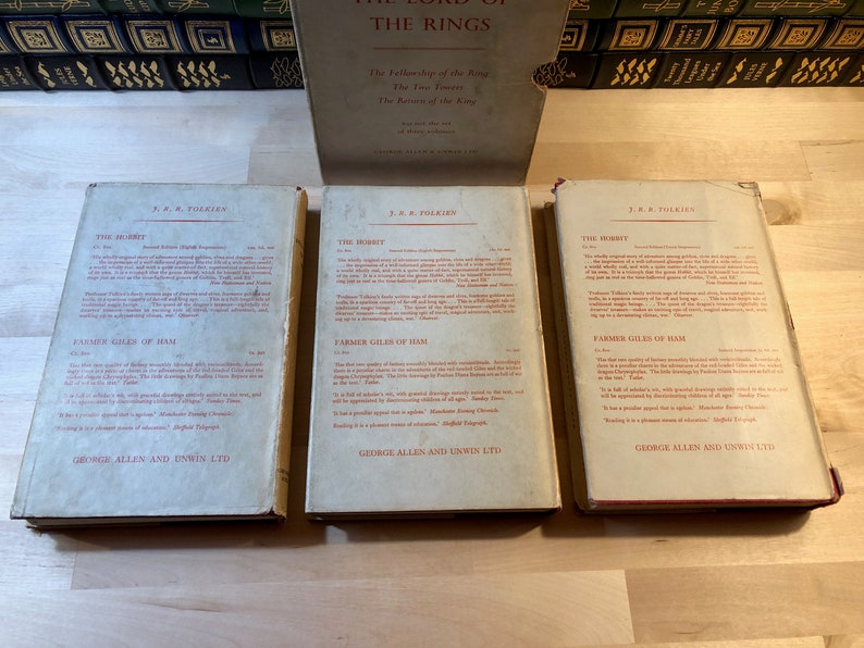 May include: Three vintage paperback books with red and white text on a white background. The books are titled "The Hobbit" by J.R.R. Tolkien. The books are published by George Allen and Unwin Ltd.