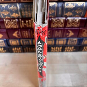 May include: A book spine featuring a red background with white text that reads Pippi Longstocking. The spine shows signs of wear, including frayed edges and peeling paper at the top. The book is positioned vertically, displaying its narrow side.