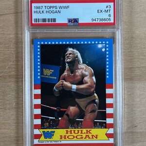 May include: A 1987 Topps WWF Hulk Hogan trading card, graded and encased in a protective holder. The card features a color image of Hulk Hogan in a wrestling pose, with the WWF logo and text in red, white, and blue.