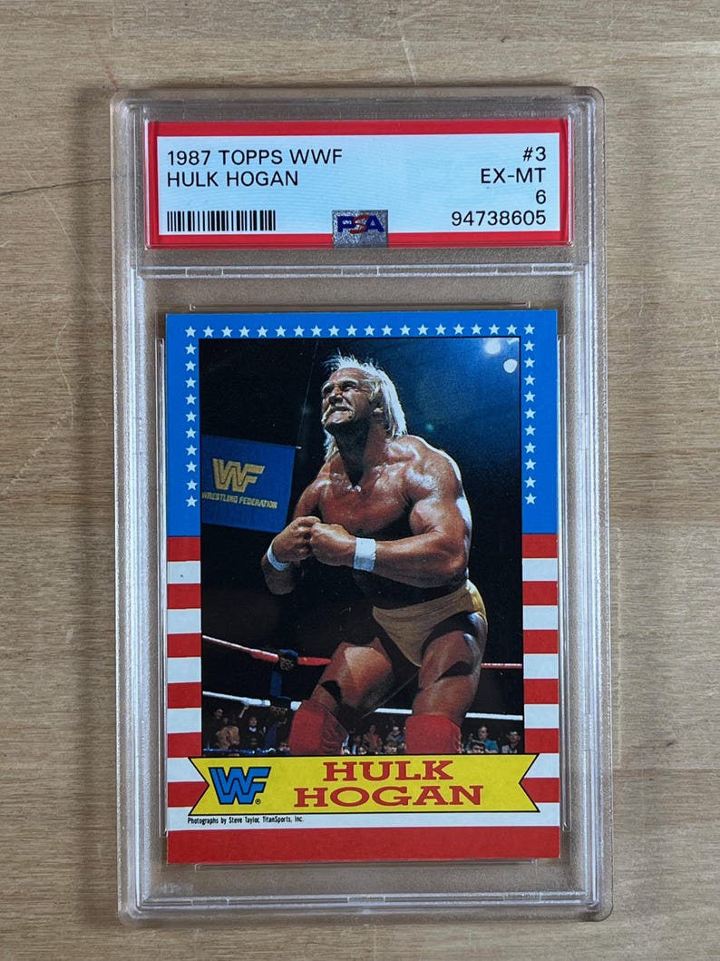 May include: A 1987 Topps WWF Hulk Hogan trading card, graded and encased in a protective holder. The card features a color image of Hulk Hogan in a wrestling pose, with the WWF logo and text in red, white, and blue.