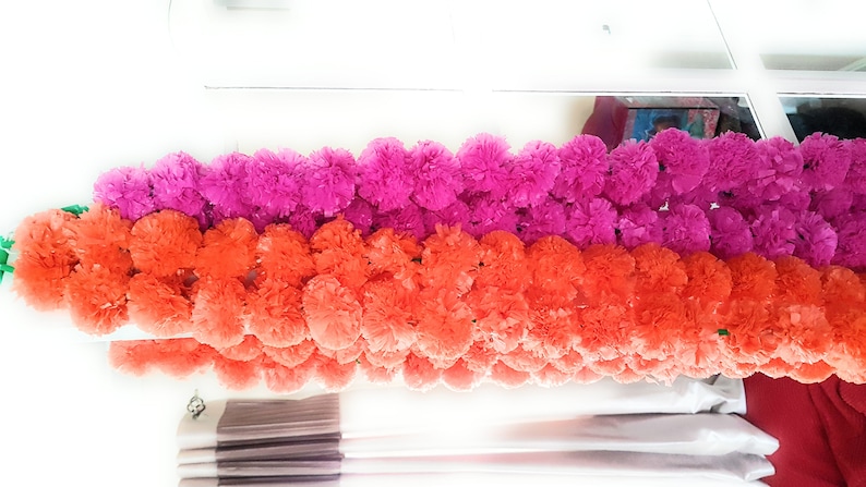 May include: A garland of artificial flowers, with two rows of pink and orange pom-poms.