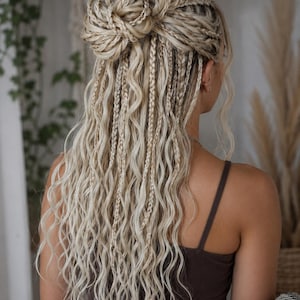 May include: Long, wavy, platinum blonde hair styled in a half-up bun with multiple thin braids integrated throughout the length. The hair features a mix of tight, small braids and loose, flowing waves that cascade down the back in a layered texture.