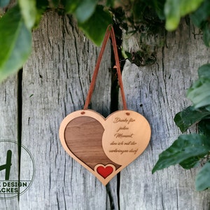 May include: A wooden heart-shaped ornament with a red heart cutout and the text "Danke für jeden Moment, den ich mit dir verbringen darf" engraved on the right side.