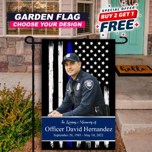 May include: A black garden flag featuring a portrait of a police officer in uniform, with a blue stripe and American flag design. The flag includes the text "In Loving Memory of Officer David Hernandez" and dates. The top banner reads "GARDEN FLAG CHOOSE YOUR DESIGN".