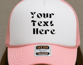 May include: A pink and white trucker hat with the text "Your Text Here" in black. The hat has a pink bill and mesh back, with a white front panel. The hat is a classic style, perfect for casual wear.