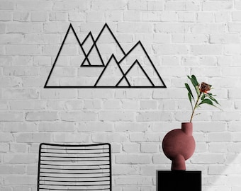 May include: A black metal wall art piece featuring a geometric mountain range design with interconnected triangular peaks. The linear structure is mounted on a white brick wall above a black chair and a vase with a single flower.