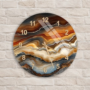 May include: A round wall clock featuring a printed agate stone pattern with swirling layers of brown, amber, cream, and blue. The clock face displays gold-colored numbers from 1 to 12 and thin gold-colored hour, minute, and second hands.