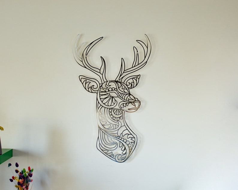 May include: A black metal deer head wall decor with intricate, detailed patterns. The deer head is a silhouette with a stylized design.