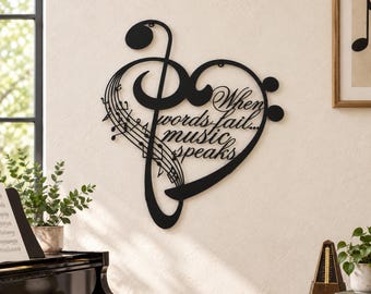 May include: A black metal wall art piece shaped like a heart combined with a treble clef and musical staff lines. The text "When words fail... music speaks" is cut out from the center of the heart design in a cursive script font.