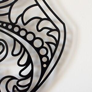 May include: Black and white decorative metal design with intricate floral patterns and a series of small circles.