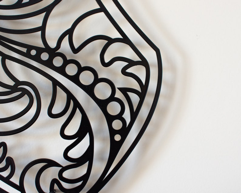 May include: Black and white decorative metal design with intricate floral patterns and a series of small circles.
