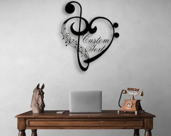 Peut inclure: Une décoration murale en métal noir en forme de cœur, intégrant une clé de sol et des portées musicales. Le design présente le texte Custom Text en écriture cursive, intégré dans la forme du cœur sur le côté droit.