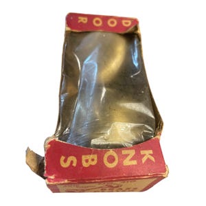 May include: A vintage door knob in its original packaging. The packaging is a red and yellow cardboard box with the words "DOOR KNOBS" printed on it. The knob is a shiny brass color.