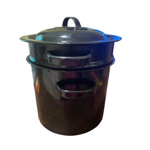 May include: A black enamel stock pot with a matching lid and two side handles. The pot features a cylindrical body with a slightly wider rim at the top. The lid has a central handle and fits securely over the opening of the deep cooking vessel.