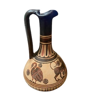May include: A ceramic jug with a dark handle and spout. The jug features a beige body with brown and red painted designs, including a swan and a lion. The neck and handle are dark brown.