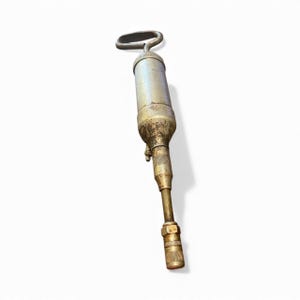 Pode incluir: Uma pistola de graxa antiga com corpo prateado e bico de lat&atilde;o. A al&ccedil;a tem formato de la&ccedil;o. A pistola mostra sinais de desgaste, com alguma ferrugem e descolora&ccedil;&atilde;o. &Eacute; projetada para dispensar graxa.
