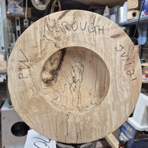 May include: A close-up of a wooden bowl with a natural wood grain pattern. The bowl is unfinished and has a rough texture. The words "ROUGH", "PM", and "1/8" are written on the side of the bowl.