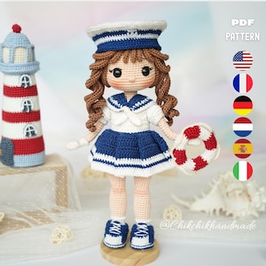 May include: A handcrafted crochet doll in a sailor's uniform, including a hat, skirt, and shoes. The doll holds a life preserver. A crochet lighthouse is on the left. The text "PDF PATTERN" is visible.