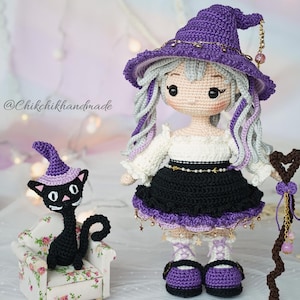 May include: A crochet doll with light gray hair wearing a purple pointed hat, white blouse, and black skirt, holding a brown staff. Beside the doll sits a small black crochet cat wearing a purple hat on a miniature floral armchair. Text reads @Chikchikhandmade.