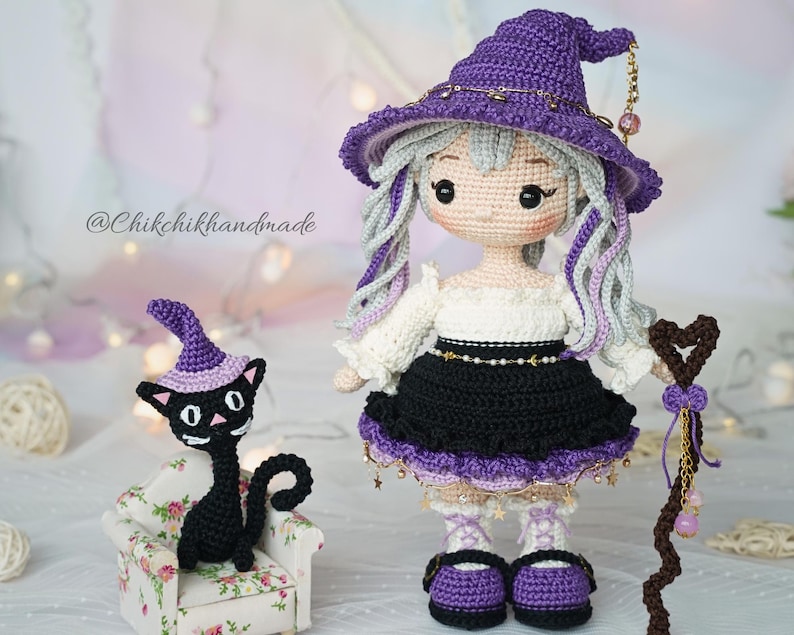 May include: A crochet doll with light gray hair wearing a purple pointed hat, white blouse, and black skirt, holding a brown staff. Beside the doll sits a small black crochet cat wearing a purple hat on a miniature floral armchair. Text reads @Chikchikhandmade.