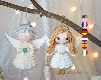 May include: Two crocheted angel ornaments hanging from a branch. The left angel has silver hair, white wings, and holds a green clover. The right angel has long blonde hair, white wings, a gold halo, and holds a small gold sphere ornament.