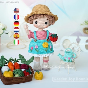 以下が含まれることがあります： ピンクのトップス、青いオーバーオール、麦わら帽子を身に着けた手作りの編み人形。人形は赤いトマトを持っており、編み野菜のミニチュアバスケットと白い椅子の上の小さな青いじょうろの隣に立っています。「Garden Joy Bonnie」というテキストが表示されます。