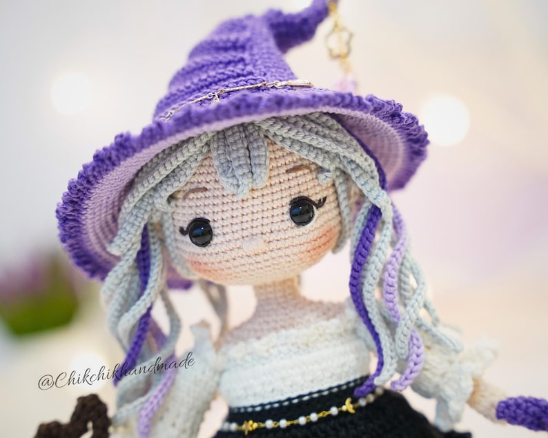 May include: A handcrafted crochet doll featuring light gray hair with purple accents, wearing a pointed purple hat with a gold star charm. The doll has black button eyes, a white top, and a black skirt with a gold beaded belt. Text reads @Chikchikhandmade.