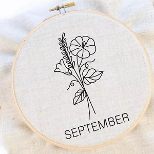 Puede incluir: Arte de bordado en un aro con un dibujo de l&iacute;nea negra de una flor y hojas. El texto "SEPTEMBER" est&aacute; escrito debajo de la flor.