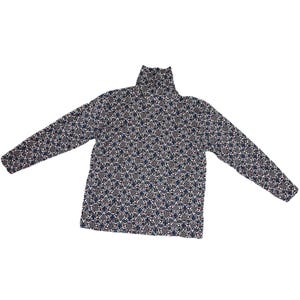 May include: A long-sleeved turtleneck shirt with a repeating floral pattern in navy blue, gray, and red on a cream background. The shirt is made of a soft, comfortable material.
