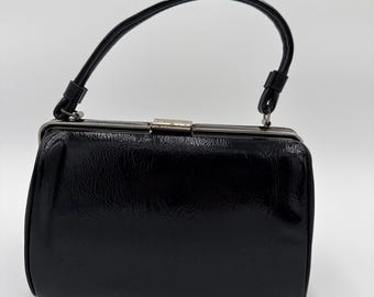 Bolsa vintage dos anos 50/60 em vinil envernizado preto, com alça superior, fecho de encaixe e armação clássica.