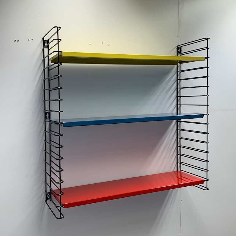 May include: A black metal wall shelf with three shelves. The top shelf is yellow, the middle shelf is blue, and the bottom shelf is red.