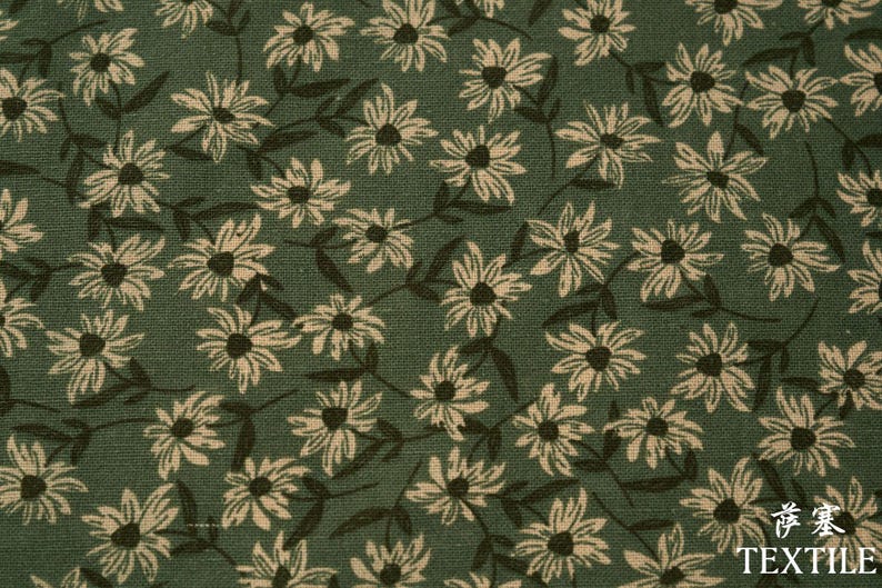 Peut inclure: Gros plan sur un tissu vert avec un motif r&eacute;p&eacute;t&eacute; de marguerites blanches avec des centres et des tiges brun fonc&eacute;. Le mot "TEXTILE" est imprim&eacute; en blanc en bas &agrave; droite.