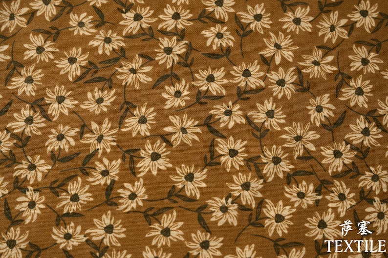 Peut inclure: Gros plan sur un tissu marron avec un motif floral r&eacute;p&eacute;titif. Le motif pr&eacute;sente des fleurs en forme de marguerites blanc cass&eacute; avec des centres et des tiges brun fonc&eacute;. Le mot "TEXTILE" est visible en bas &agrave; droite.