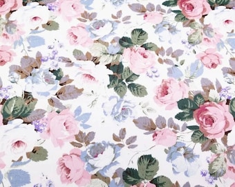 May include: A white fabric with a pink and blue floral pattern. The fabric is covered in roses and leaves.