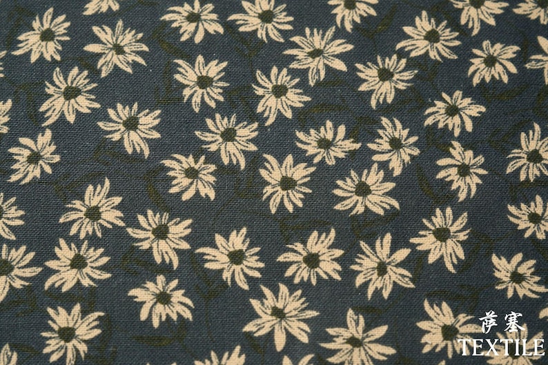 Peut inclure: Tissu bleu fonc&eacute; avec un motif r&eacute;p&eacute;t&eacute; de fleurs en forme de marguerites de couleur cr&egrave;me. Les fleurs ont des centres fonc&eacute;s et sont dispers&eacute;es sur le tissu. Le tissu a un aspect textur&eacute;.