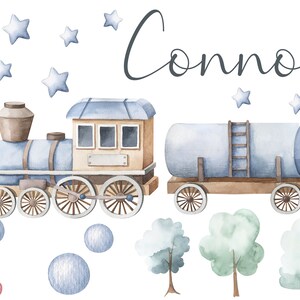 Könnte beinhalten: Eine Aquarell-Illustration eines blauen Zuges mit einem braunen Schlusslicht, einem blauen Tankwagen und einer Holzleiter. Der Zug ist von blauen Sternen und blauen und weißen Punkten umgeben. Der Name "Connor" ist in Kursivschrift über dem Zug geschrieben.