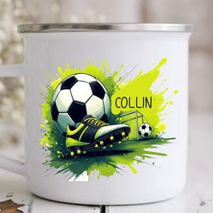 May include: White enamel mug featuring a soccer theme. The design includes a soccer ball, cleats, and a small goal, set against a green and yellow splash background. The name "COLLIN" is also displayed.