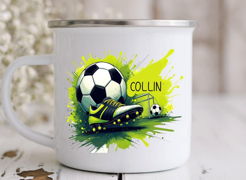 May include: White enamel mug featuring a soccer theme. The design includes a soccer ball, cleats, and a small goal, set against a green and yellow splash background. The name "COLLIN" is also displayed.