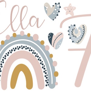 Könnte beinhalten: Ein Regenbogen mit rosa, blauen und goldenen Streifen, verziert mit schwarzen und weißen Punkten. Der Regenbogen ist von Herzen und Sternen umgeben. Der Name "Ella" ist in rosa Schrift über dem Regenbogen geschrieben. Die Zahl "7" ist in rosa Schrift rechts neben dem Regenbogen geschrieben.