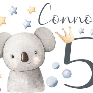 Könnte beinhalten: Eine Aquarell-Illustration eines Koalas mit einer Krone, der Zahl 5 und dem Namen Connor. Die Illustration ist von blauen und gelben Sternen umgeben.