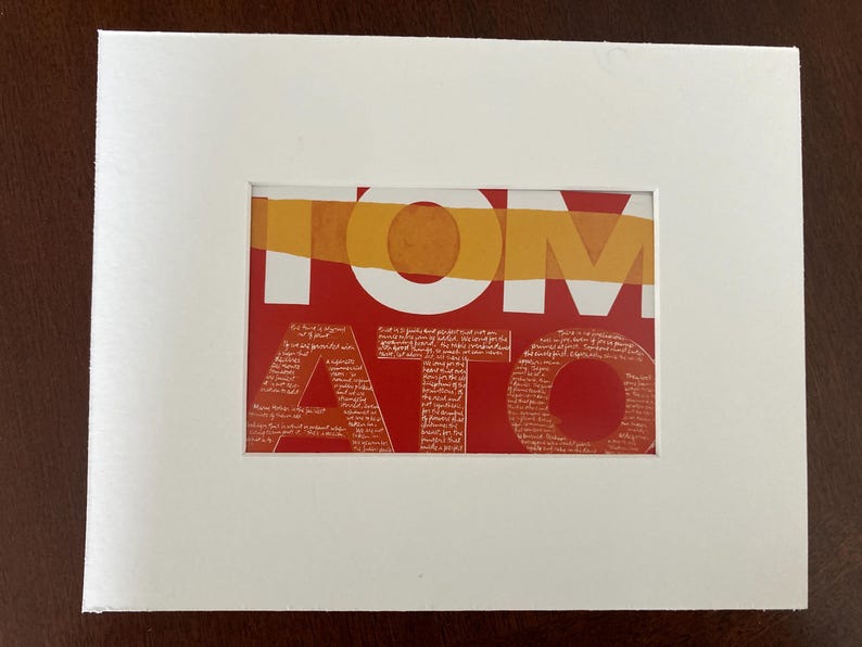 Op de afbeelding: Een ingelijste kunstdruk met het woord "TOMATO" in grote witte letters op een rode achtergrond. De letters zijn bedekt met een textuurpatroon. Een horizontale oranje streep loopt over de bovenkant. De print is in een witte passe-partout.