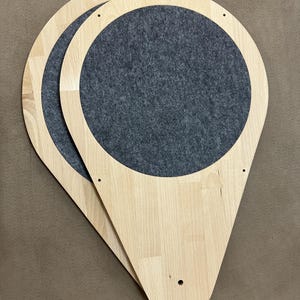 Op de afbeelding: Twee houten kattenplanken met een druppelvorm en een cirkelvormige grijze vilten inzet. De planken zijn gemaakt van lichtgekleurd hout en hebben voorgeboorde gaten voor montage. Ontworpen voor katten, ze meten ongeveer 40 cm lang.