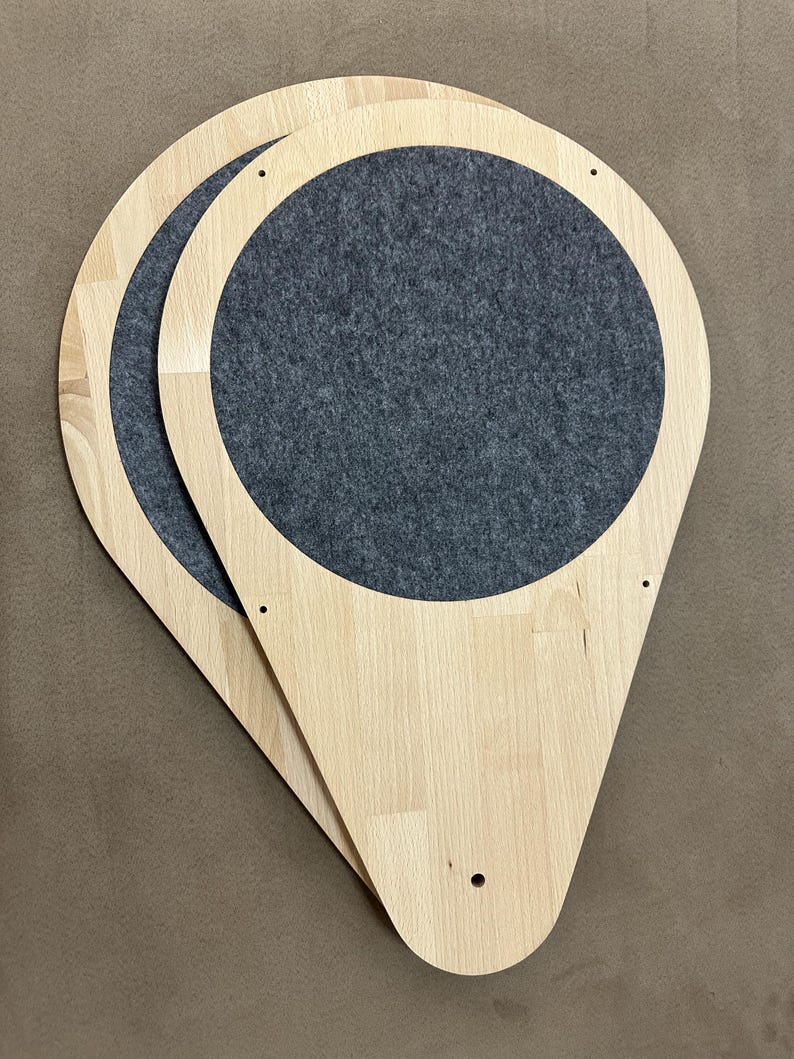 Op de afbeelding: Twee houten kattenplanken met een druppelvorm en een cirkelvormige grijze vilten inzet. De planken zijn gemaakt van lichtgekleurd hout en hebben voorgeboorde gaten voor montage. Ontworpen voor katten, ze meten ongeveer 40 cm lang.