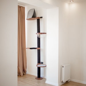 Peut inclure: Un arbre &agrave; chat du sol au plafond dot&eacute; d'un poteau central envelopp&eacute; de sisal noir avec quatre plateformes en bois. Le niveau sup&eacute;rieur poss&egrave;de une capuche en feutre gris, le deuxi&egrave;me niveau inclut un bol en acrylique transparent.