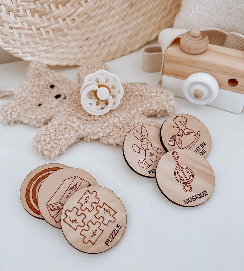 May include: Wooden circle puzzle pieces with various images, including a rainbow, a rocking horse, a musical note, a puzzle, and a bunny. The text on the pieces reads "Jet en Ois", "Musique", and "Puzzle".